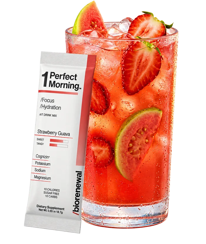 Glass of One Perfect Morning Strawberry Guava over ice with strawberries and guava, next to its stick pack