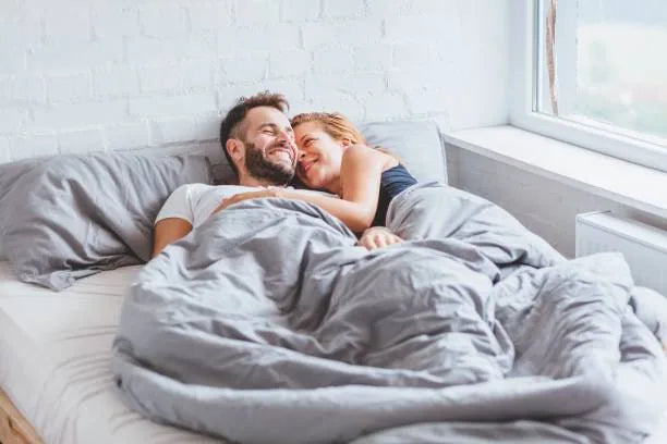 A smiling couple waking up together in bed